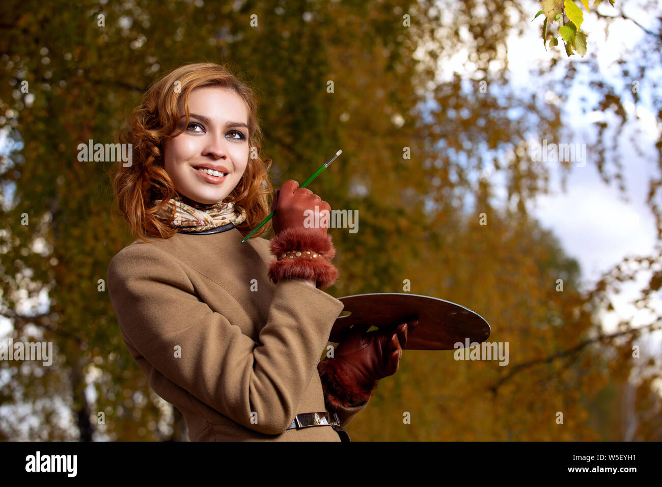 Junge Frau mit Palette und Pinsel im Freien im Herbst Park posieren. Stockfoto