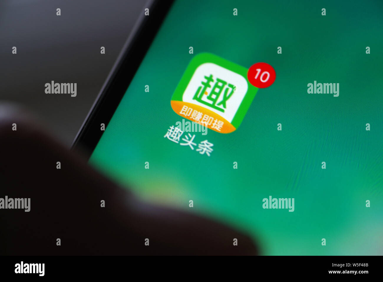 ---- Eine chinesische Mobiltelefon Benutzer zeigt ein Symbol der chinesischen News und video Aggregation app Qutoutiao auf seinem Smartphone in Ji'nan City, East China Stockfoto
