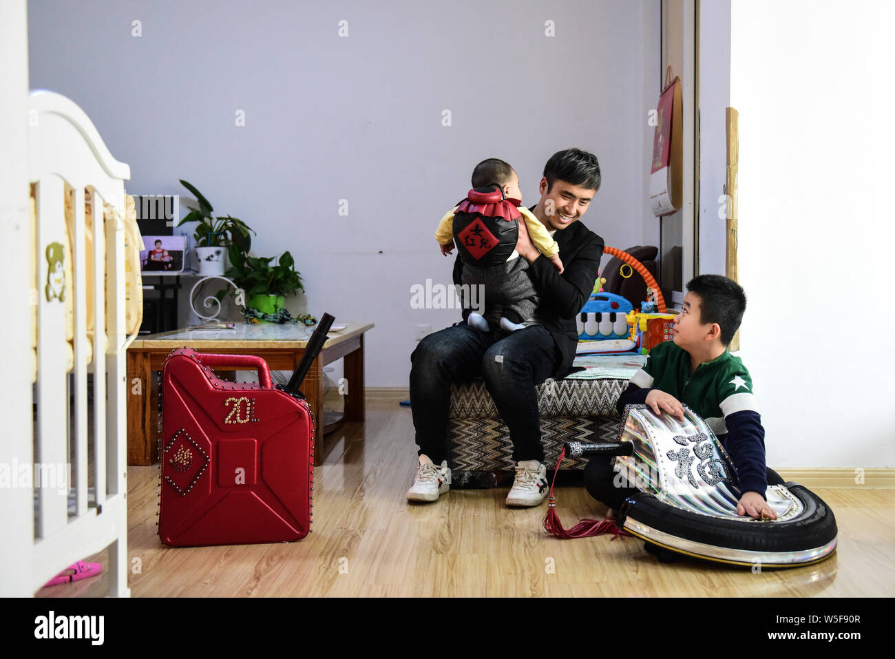 36-Jahre alten Chinesischen leder Handwerker Zhang Renbing und seine Kinder posieren mit Produkte aus Leder mit Form der Schwerter und Betankung Schaufel von ihm gemacht Stockfoto