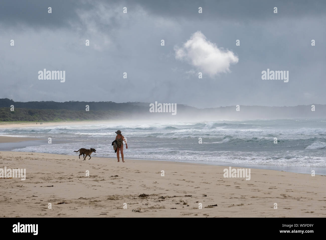 Ein Schwimmer aus dem Wasser auf einem einsamen Strand und kehrt in ihren Sonnenschirm Stockfoto