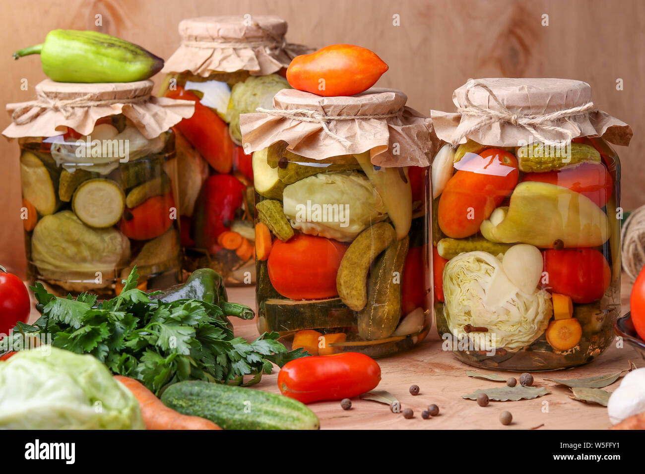 Sortierte eingelegtes Gemüse in Gläsern: Gurken, Tomaten, Kohl, Zucchini und Paprika mit Knoblauch, Dill und Lorbeerblätter in Gläsern auf einem hölzernen backgroun Stockfoto