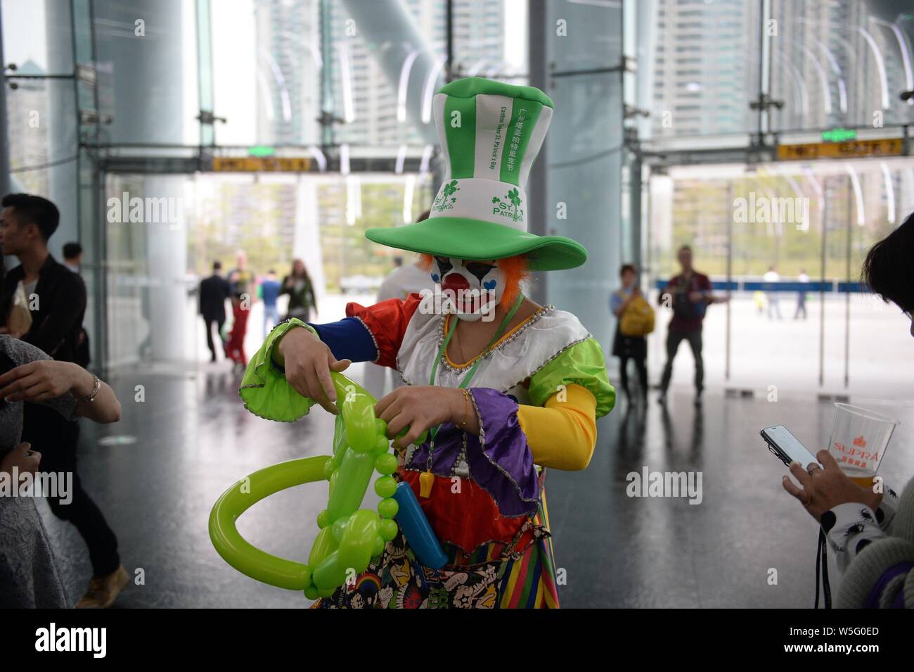 Ein Clown führt die Saint Patrick's Day vor der Kanton Turm, ein Wahrzeichen in Guangzhou zu feiern, gebadet in grün in Guangzhou City, South Stockfoto