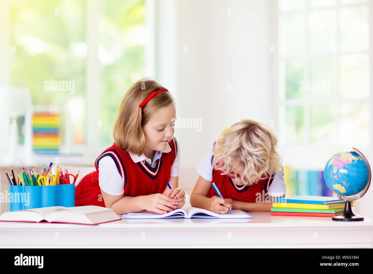 Kinder gehen wieder zur Schule. Kinder Studieren und Lernen für Vorschulkinder. Jungen und Mädchen der Grundschule klasse Hausaufgaben machen. Schlafzimmer mit Schreibtisch, Bücher und Globus fo Stockfoto