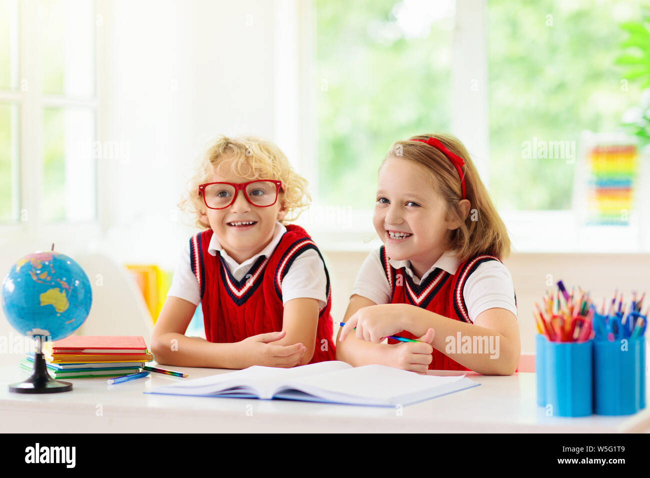 Kinder gehen wieder zur Schule. Kinder Studieren und Lernen für Vorschulkinder. Jungen und Mädchen der Grundschule klasse Hausaufgaben machen. Schlafzimmer mit Schreibtisch, Bücher und Globus fo Stockfoto