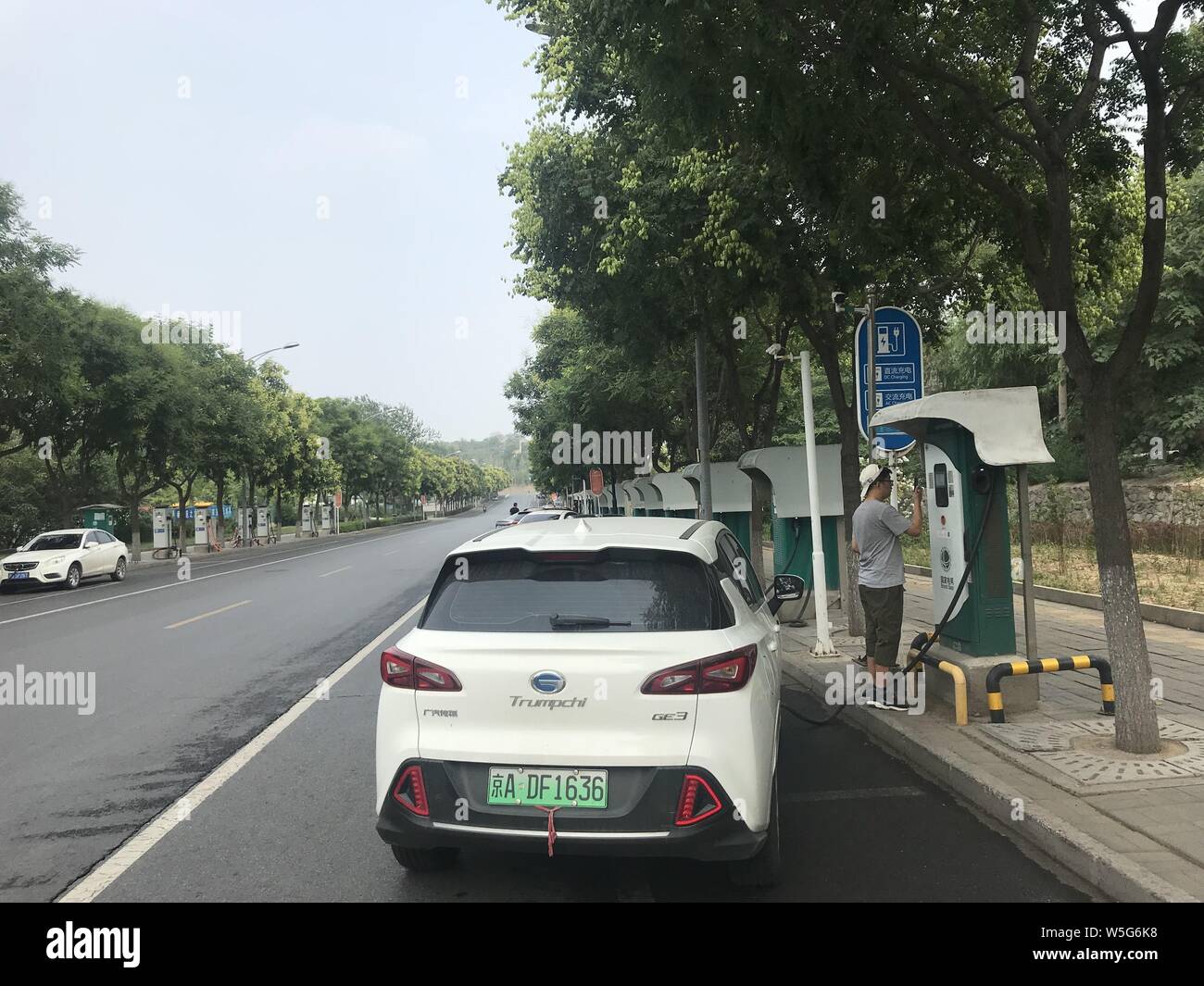 Peking, China. Am 15. Juli 2019. Foto mit einem Handy aufgenommen zeigt einen Mann sein Elektrofahrzeug aufladen an einer öffentlichen Ladestation Stapel in Shijingshan District von Peking, der Hauptstadt von China, am 15. Juli 2019. China hat den weltweit größten Netzwerk von Einrichtungen für Fahrzeuge mit Elektroantrieb, wie 1 Million Ladung Pfähle hatte bis Ende Juni abgeschlossen. Mit: China meldet das weltweit größte Netzwerk von Einrichtungen für elektrische Fahrzeuge Kredit: Ding Hongfa/Xinhua/Alamy leben Nachrichten Stockfoto