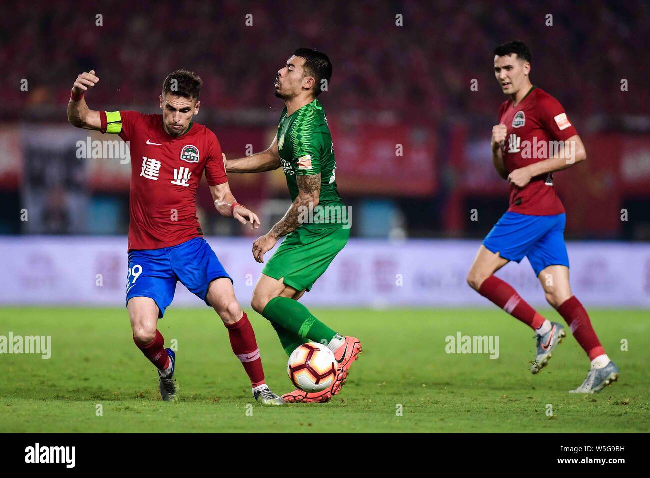 Brasilianische Fußballspieler Olivio da Rosa, auch bekannt als Ivo, Links, Henan Jianye passt den Ball gegen englische Fußballspieler Nico Yennaris, in China bekannt wie Li Ke Sinobo Guoan Peking, der in der 20. Runde während der 2019 chinesischen Fußballverband Super League (CSL) in Zhengzhou City, Central China Provinz Henan, 27. Juli 2019. Henan Jianye besiegt Beijing Guoan Sinobo 1-0. Stockfoto
