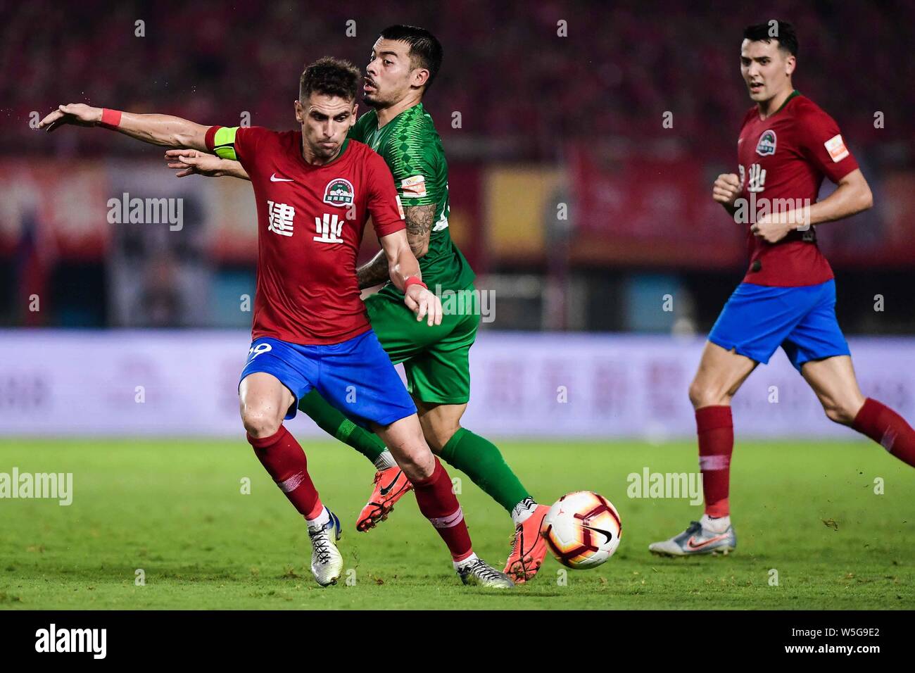 Brasilianische Fußballspieler Olivio da Rosa, auch bekannt als Ivo, Links, Henan Jianye passt den Ball gegen englische Fußballspieler Nico Yennaris, in China bekannt wie Li Ke Sinobo Guoan Peking, der in der 20. Runde während der 2019 chinesischen Fußballverband Super League (CSL) in Zhengzhou City, Central China Provinz Henan, 27. Juli 2019. Henan Jianye besiegt Beijing Guoan Sinobo 1-0. Stockfoto