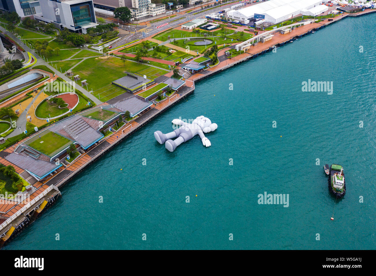 Die 37 Meter lange schwebende Skulptur von uns Künstler Kaws am Victoria Harbour in Hong Kong, China, 24. März 2019 angedockt. Die 37 Meter lange Float Stockfoto