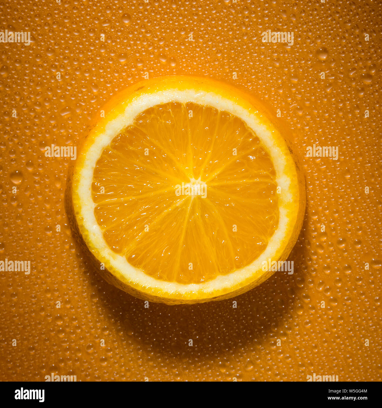 Scheibe Orange auf orange farbigen Hintergrund mit Wassertropfen erzeugen Textur - frisches und gesundes Essen Konzept Bild Stockfoto