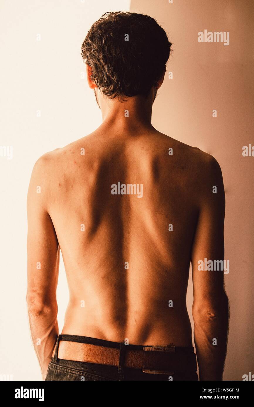 Vertikale Aufnahme eines Mannes, der graue Denim-Hosen trägt Brauner Gürtel Stockfoto