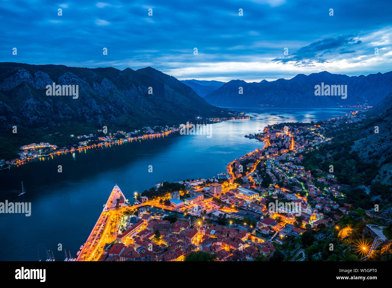 Montenegro, Bucht von Kotor Stadt Häuser, Straßen und Verkehr in der Nacht von oben durch magische Berge und Wasser der Förde nach Sonnenuntergang umgeben Stockfoto