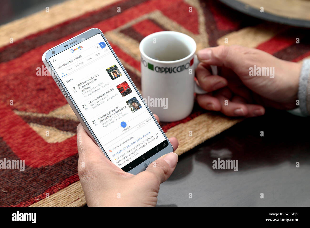 Frau mit Smartphone in den Händen. Google-Suchseite auf dem Bildschirm. Suche im Internet. Stockfoto