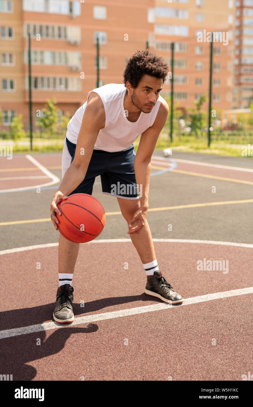 Junge basketballer in Activewear nach vorne biegen, bevor Ball Stockfoto