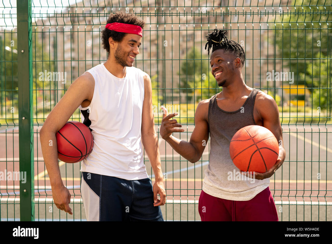 Zwei junge freundliche Basketball Spielkameraden diskutieren einige neugierige Momente des Spiels Stockfoto