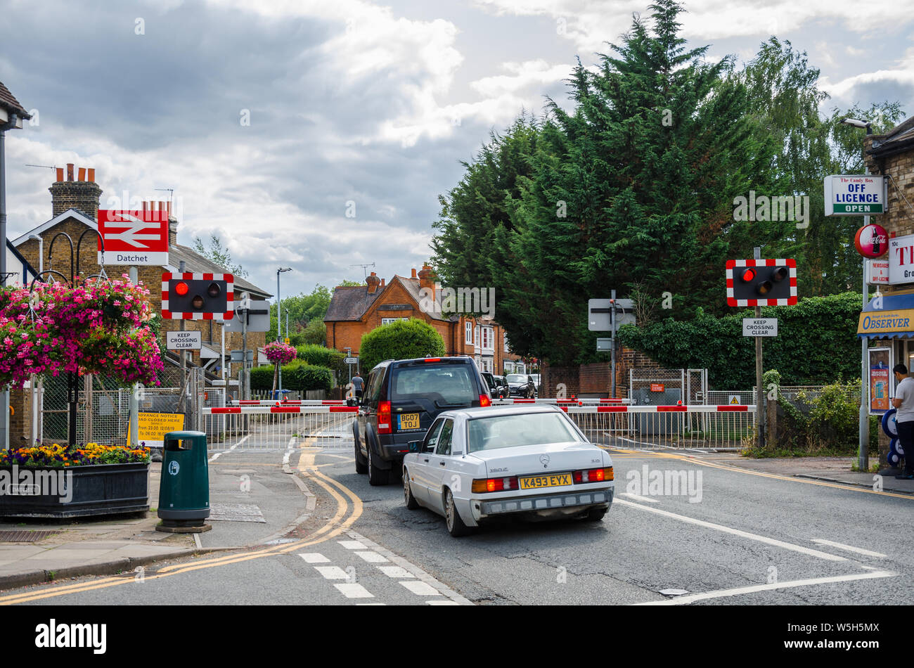 Autos warten an einem Bahnübergang am Bahnhof Datchet wie die Barrieren sind unten und Warnleuchten blinken als eines vorbeifahrenden Zuges unmittelbar bevorsteht. Stockfoto