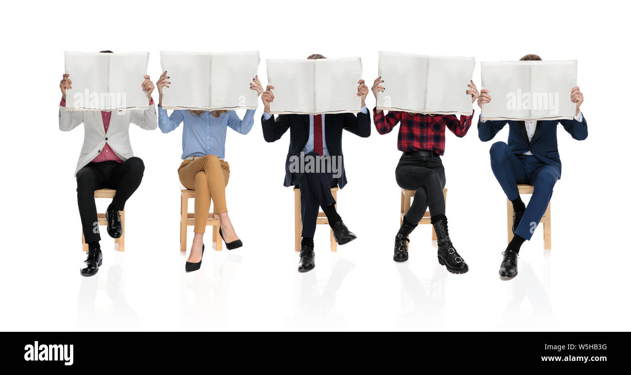 Gruppe von fünf jungen Menschen sitzen und lesen Zeitung, alle, die ihre Gesichter mit der Zeitung, auf weißem Hintergrund Stockfoto