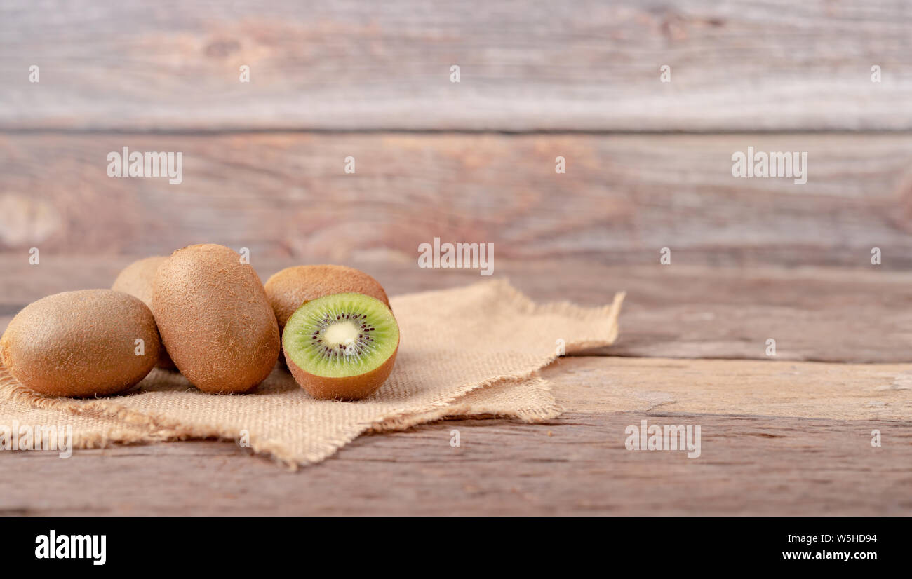 Kiwis und eine Hälfte auf den Sack auf dem Holztisch. Stockfoto