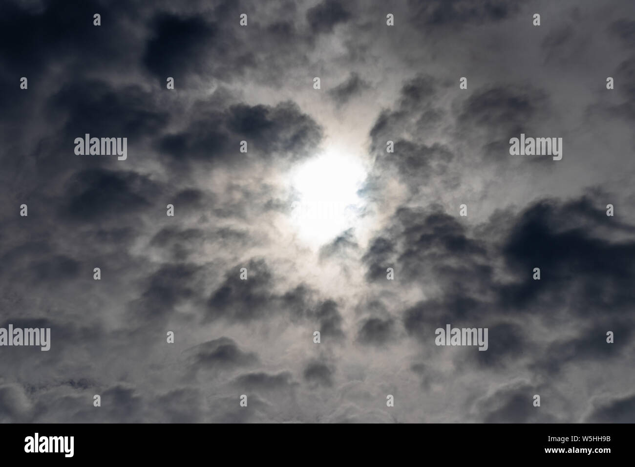 Dunkle Wolken, der Himmel schwarz, Sonne im Zentrum. Vor Regenwolken. Stockfoto