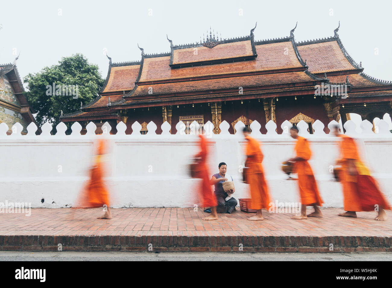 Buddhistische Mönche während der Laotischen traditionelle heilige Almosen Preisverleihung in Stadt Luang Prabang, Laos. Lange Exposition, unscharfe Objekt Stockfoto