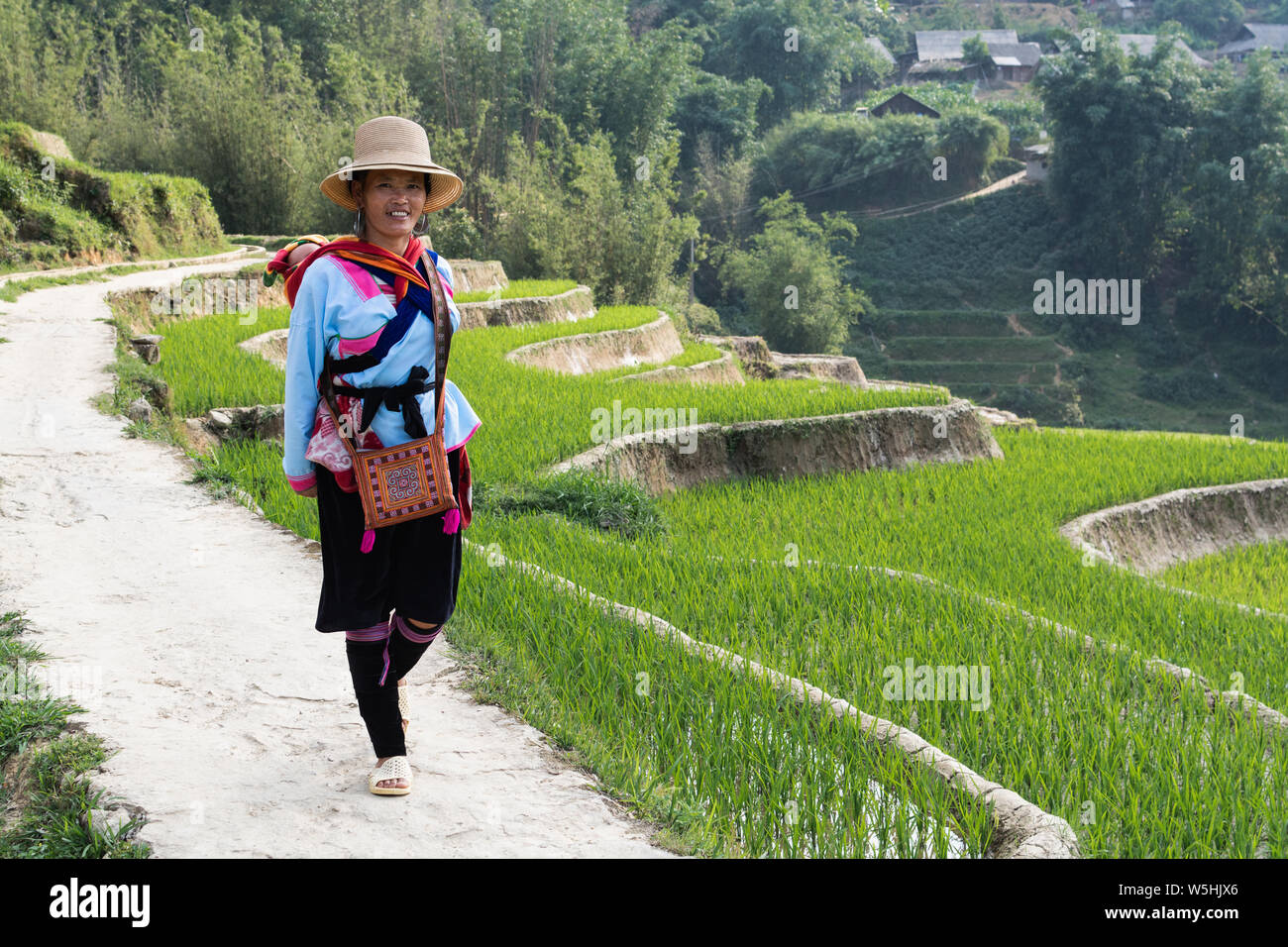 Sapa, Vietnam - Mai 2019: Frau aus der ethnischen Gruppe der Hmong in traditioneller Kleidung Wandern neben dem Reis Terrasse in Lao Cai Provinz Stockfoto