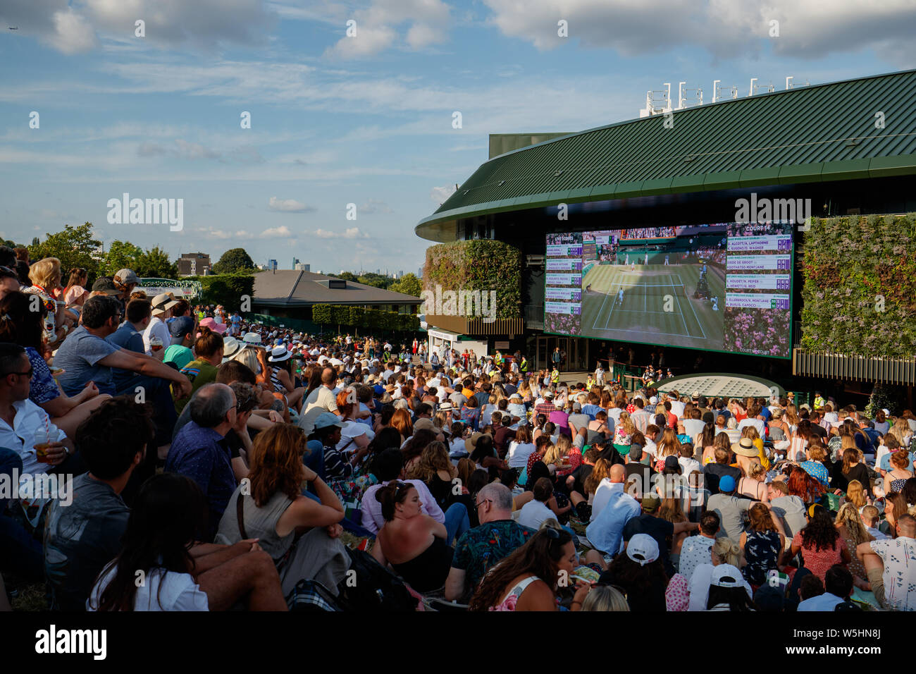 Fans und Zuschauer auf Henman Hill, Murray Damm oder Aorangi Hügel mit dem großen Bildschirm auf Nr. 1 Gericht während der Meisterschaften in Wimbledon 2019. Stockfoto