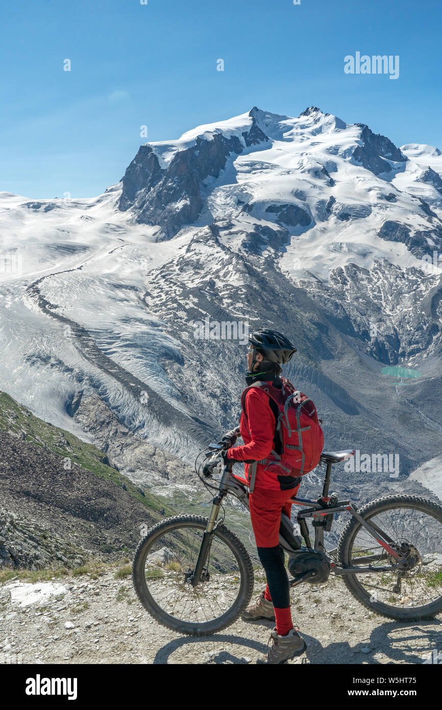 Active Senior, Frau, reiten Ihr elektrische Mountainbike auf dem Gornergrat bei Zermatt, Wallis, Schweiz. Im Hintergrund Gornergletscher, Monte Rosa Stockfoto