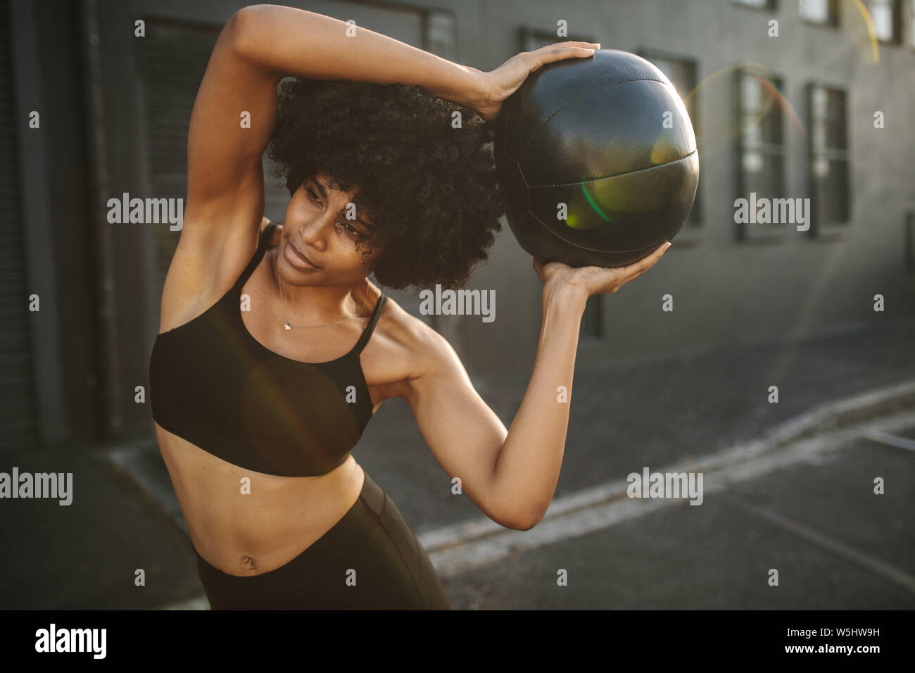 Sportlerin zu tun stretching Übung mit medizinball. Muskulöse Frau Trainieren mit Fitness Ball im Freien. Stockfoto