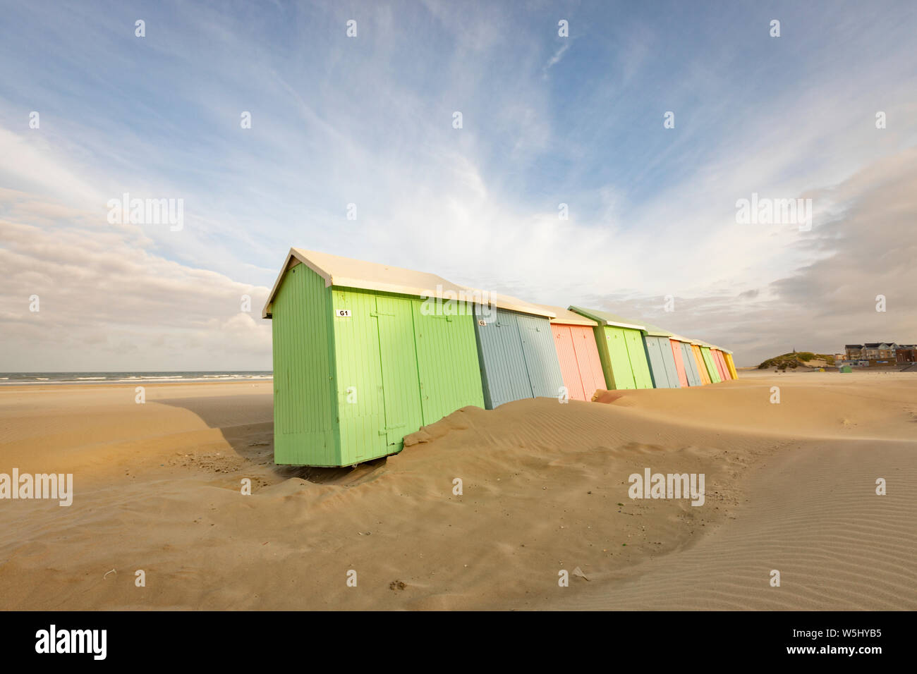 Strandhütten in Pastellfarben, geneigt aus dem Wind, an Berck-Plage, Pas-de-Calais, Frankreich Stockfoto