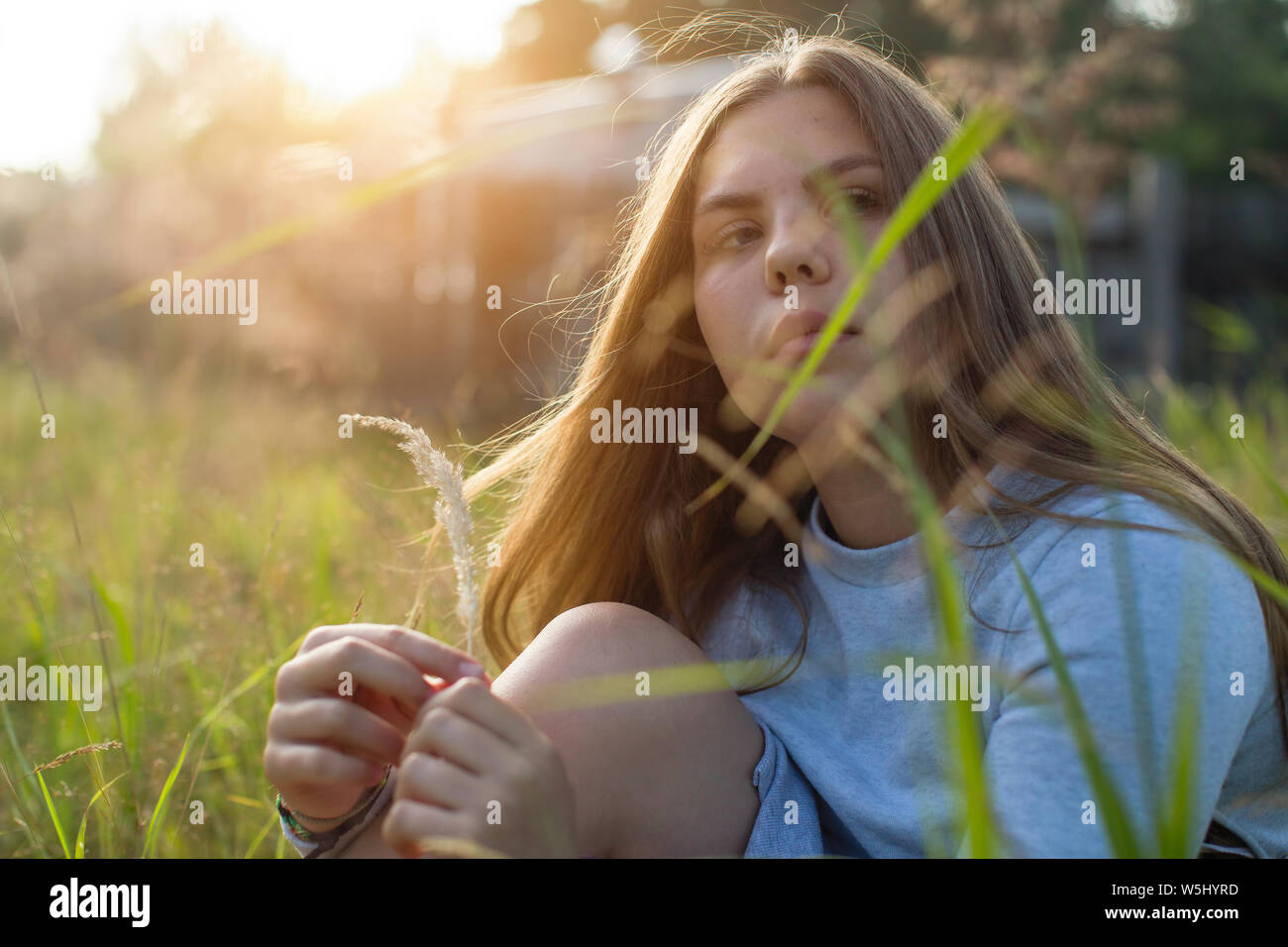 Teenage Mädchen im Gras sitzen im Sommer Landschaft bei Sonnenlicht. Stockfoto