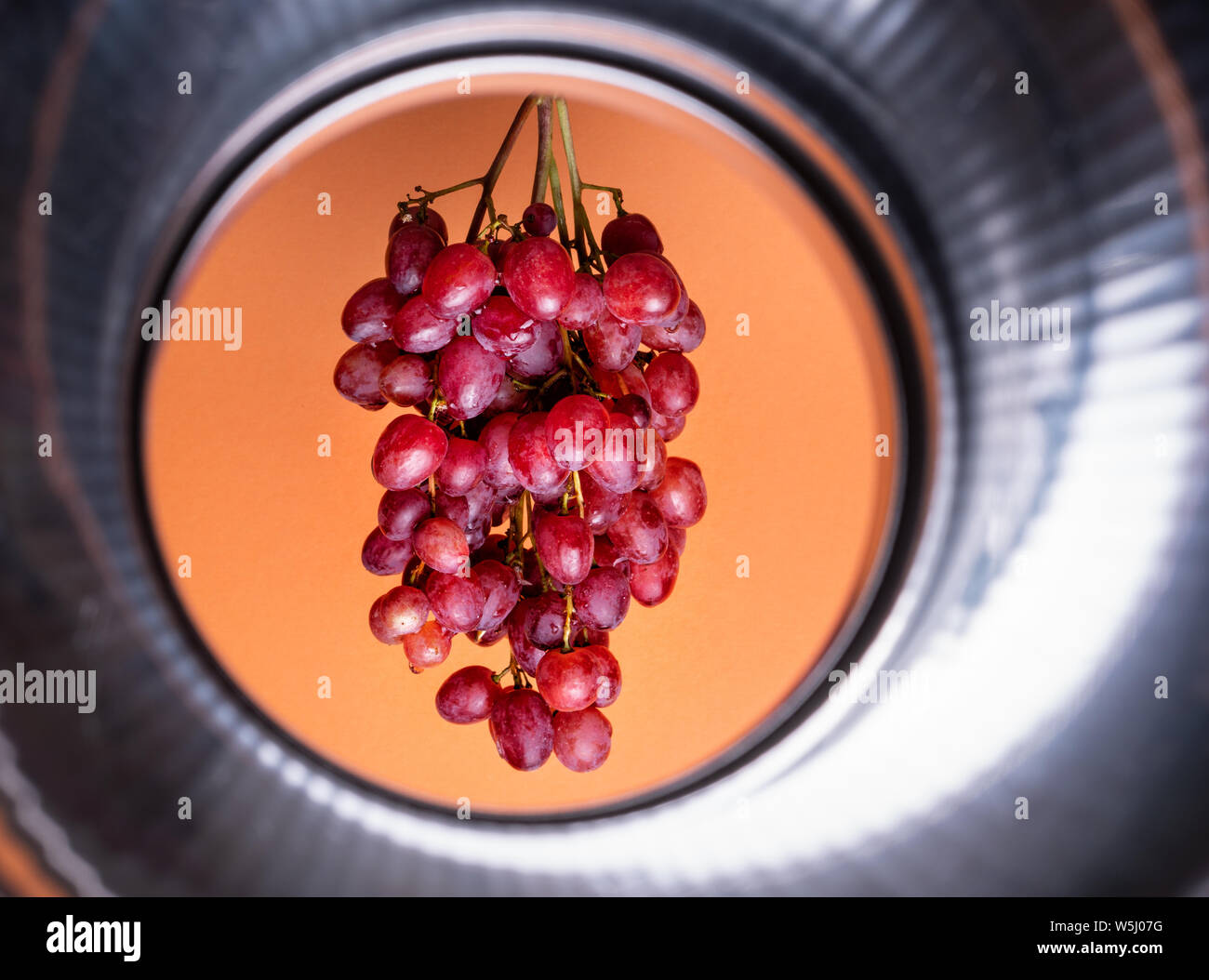 Natürliche organische Rosa saftige Trauben auf einen Trend orange Hintergrund der Vorderansicht. Im rustikalen Stil. Dorf Landwirtschaft Konzepte. Stockfoto