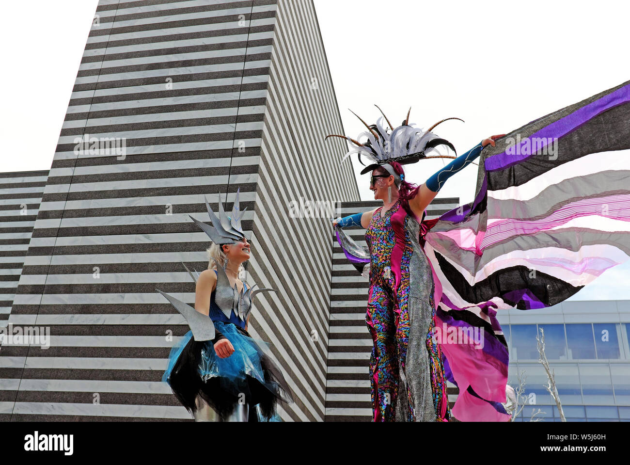 Gestelzte Frauen, die in surrealen Outfits gekleidet sind, nehmen an der Parade 2019 The Circle Procession im Wade Oval von Cleveland, Ohio, USA Teil. Stockfoto