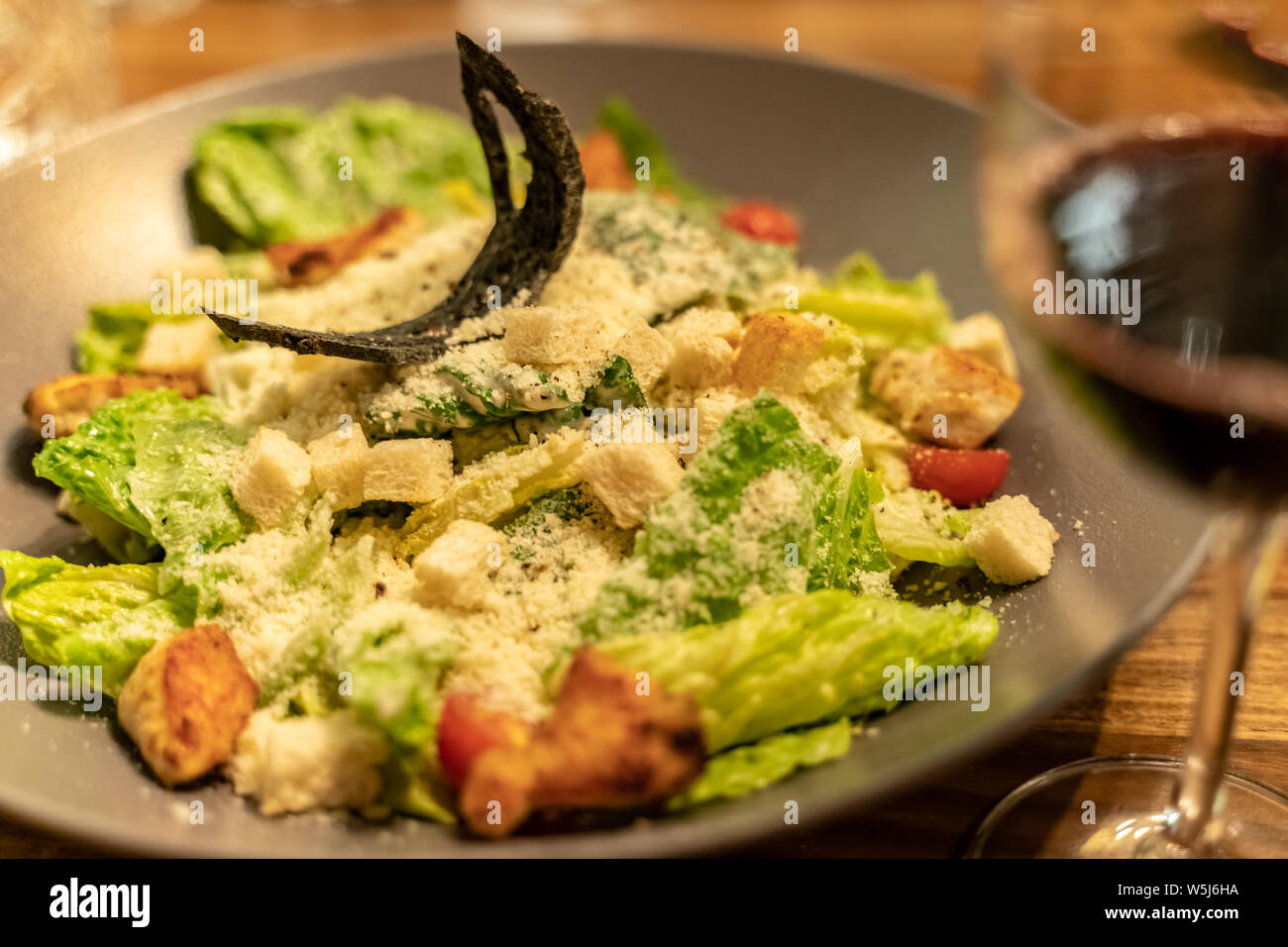 Caesar Salat mit Hühnchen, Mozzarella und Tomaten in Braun Platte auf dunklen Holztisch mit geringer Tiefenschärfe über Dark grunge Hintergrund Stockfoto