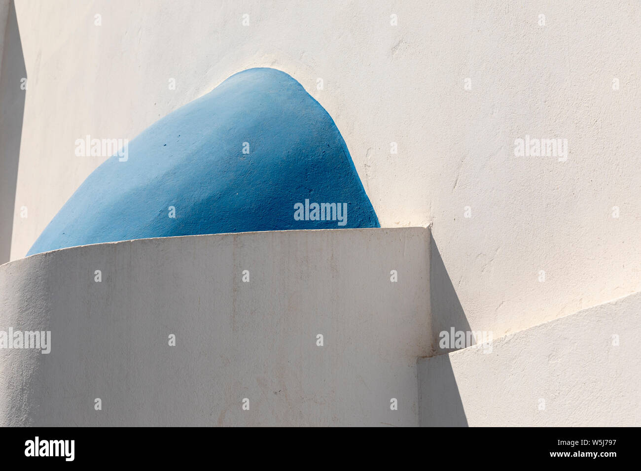 Zusammenfassung von Winkeln und Kurven von weißen Wänden und blauen Kuppeln der Gebäude in Megalochori, Santorin, Griechenland Stockfoto