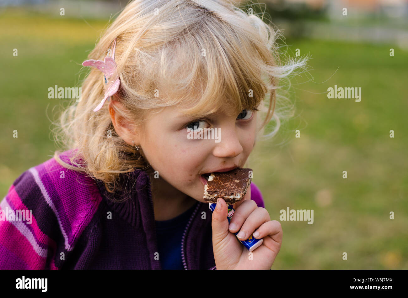 Blonde Mädchen essen einen schokoladenbiskuit Stockfoto