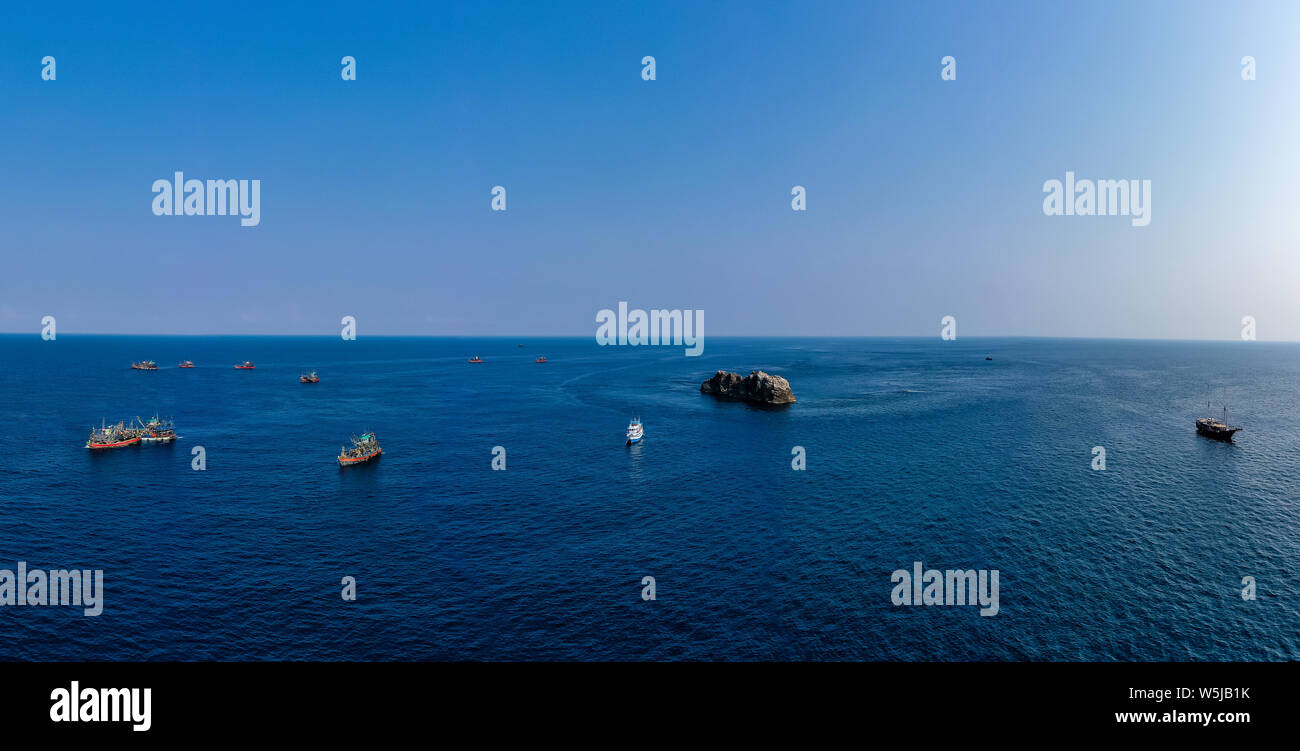 Panoramablick auf das Luftbild von eine große Flotte von Fischtrawlern und einem einzigen Tauchen Boot um einen berühmten Tauchplatz in der Mergio Archipel, Myanmar Stockfoto