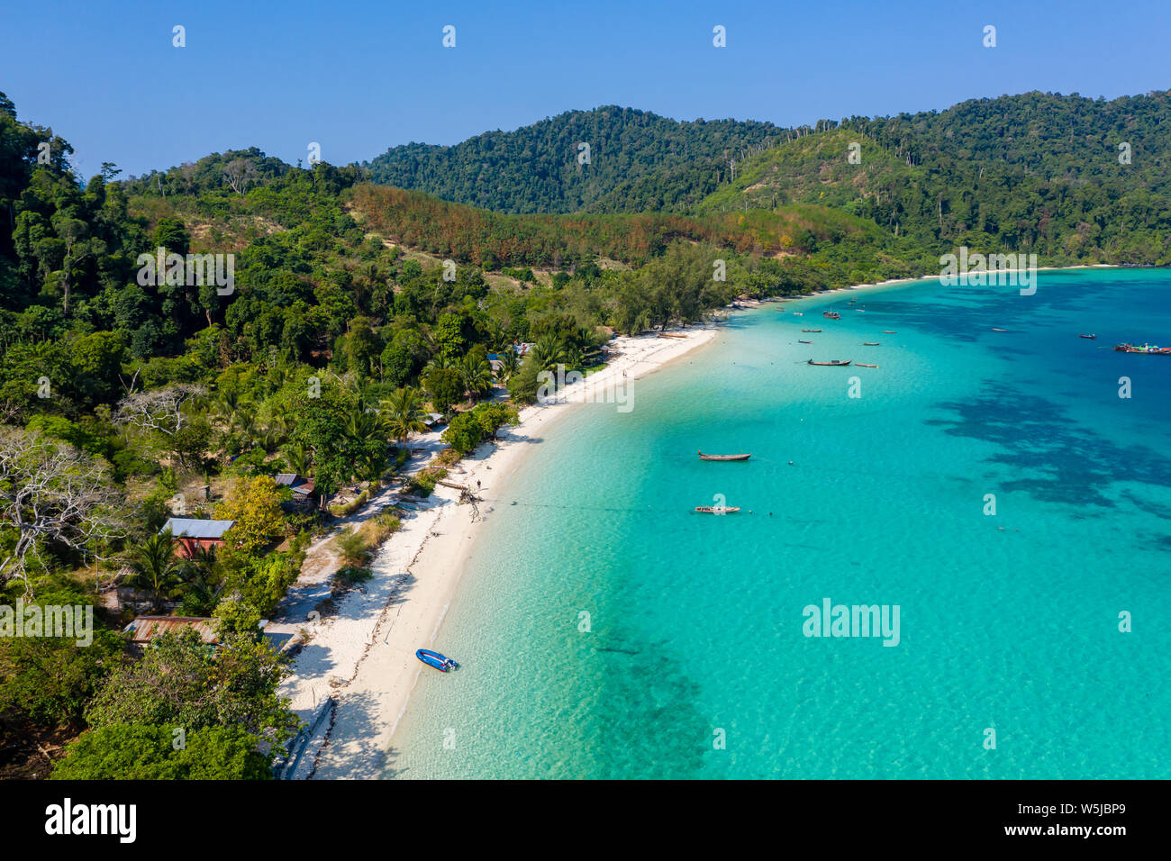 Antenne drone Blick auf die traditionellen Fischerboote vertäut über ein Korallenriff rund um eine Fernbedienung, grünen, tropischen Insel im Mergui Archipel Stockfoto