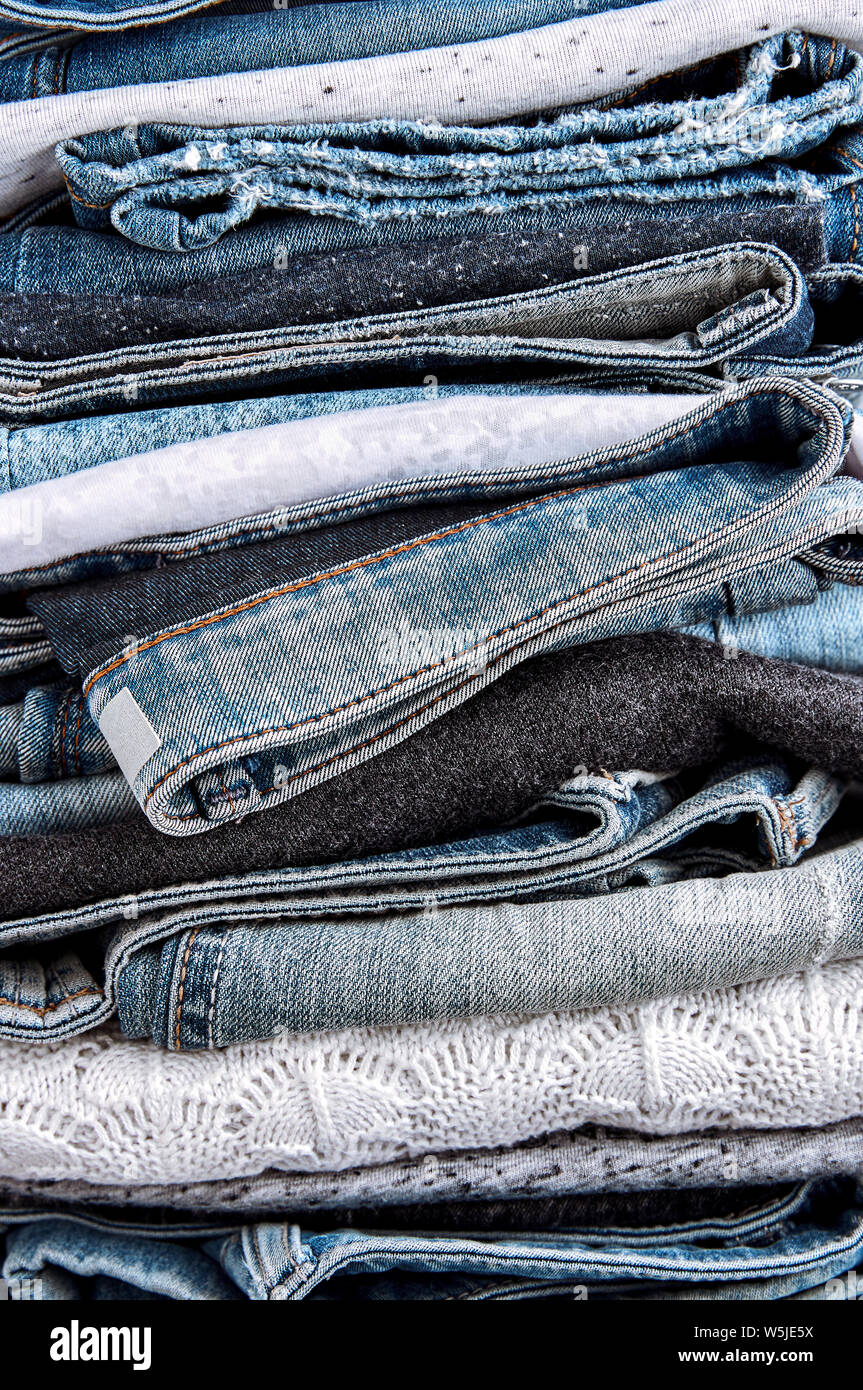 Nahaufnahme der Stapel der blauen Jeans, Pullover und Shirts Stockfoto