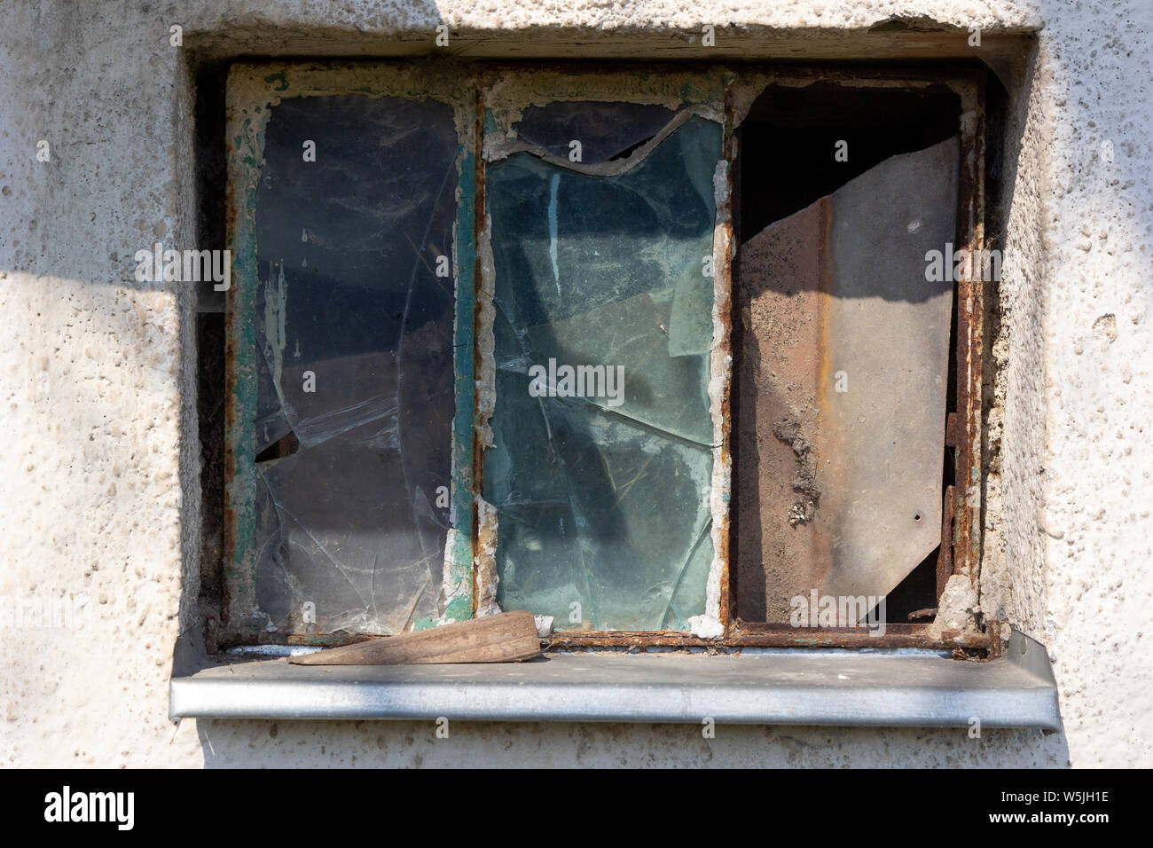 Ein rostiger Fenster mit zerbrochenen Glasscheiben Stockfoto