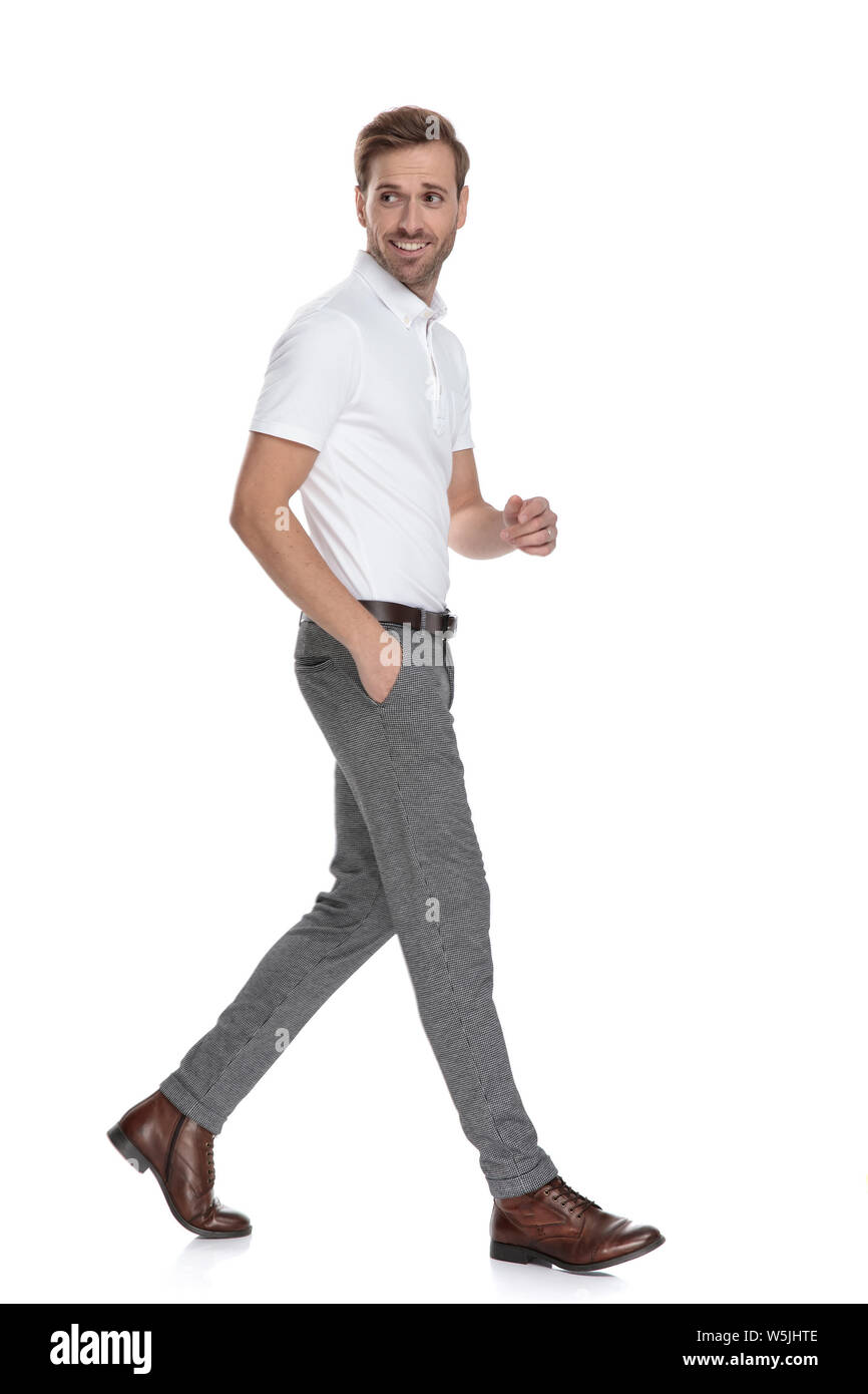 Lächelnd Smart Casual mann Spaziergänge und blickt über die Schulter auf weißem Hintergrund Stockfoto
