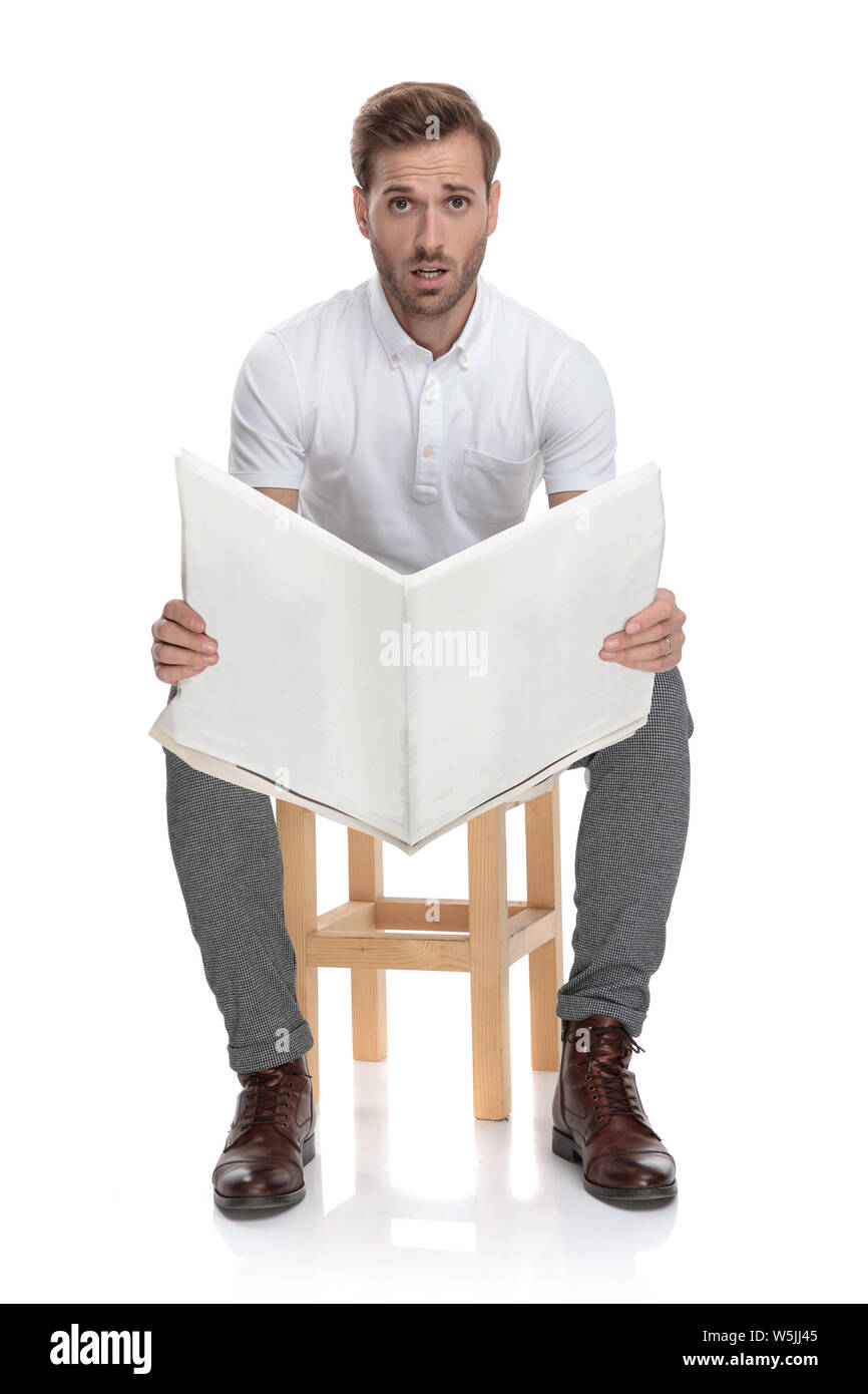 Sitzt der Mensch lesen Zeitung ist von der Nachricht schockiert auf weißem Hintergrund Stockfoto