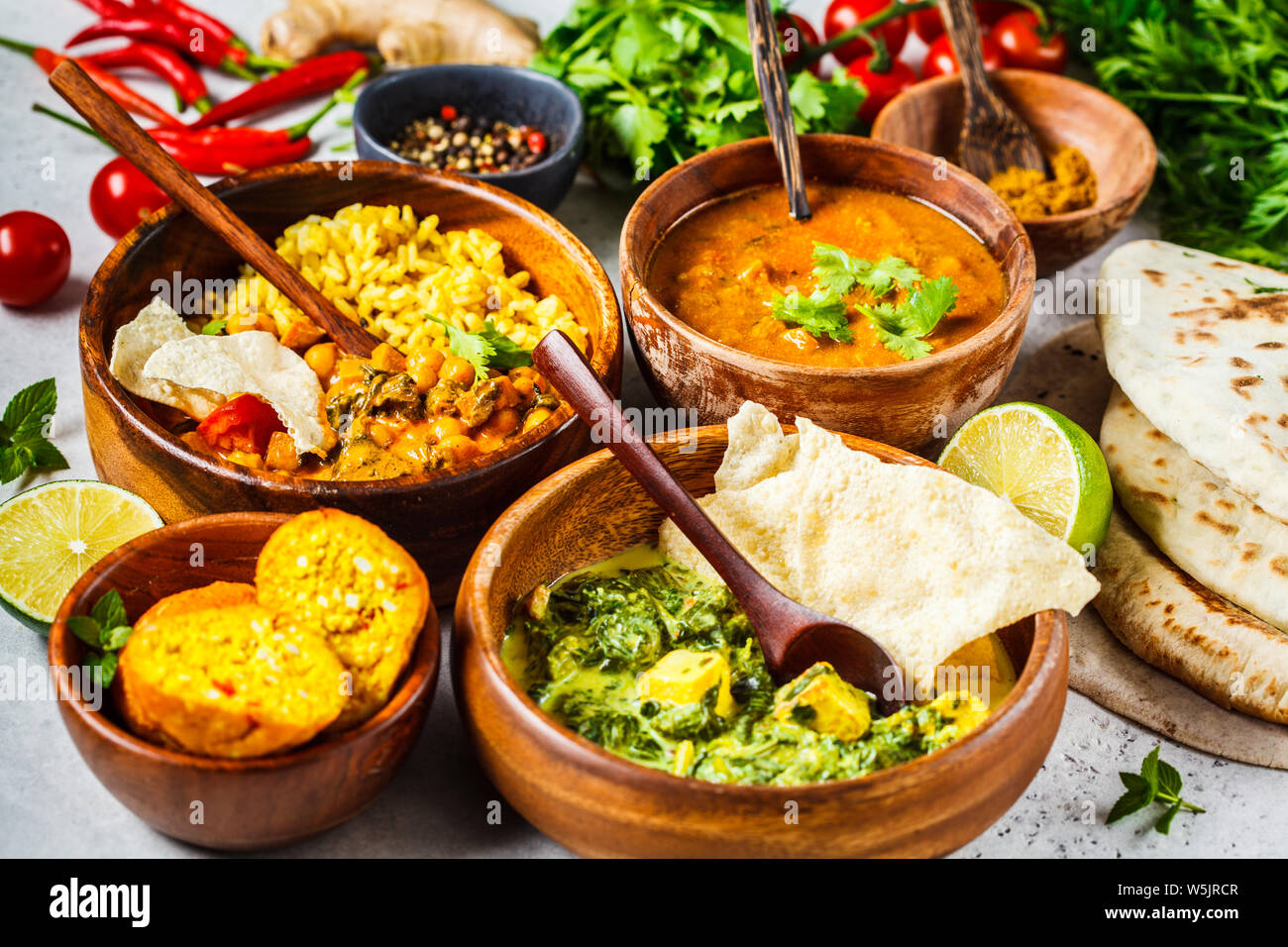 Essen traditionelle indische Küche. Dal, Palak Paneer, Käse Kugeln, Curry, Reis, Chapatis, Chutney in hölzernen Schüsseln auf weißem Hintergrund. Stockfoto