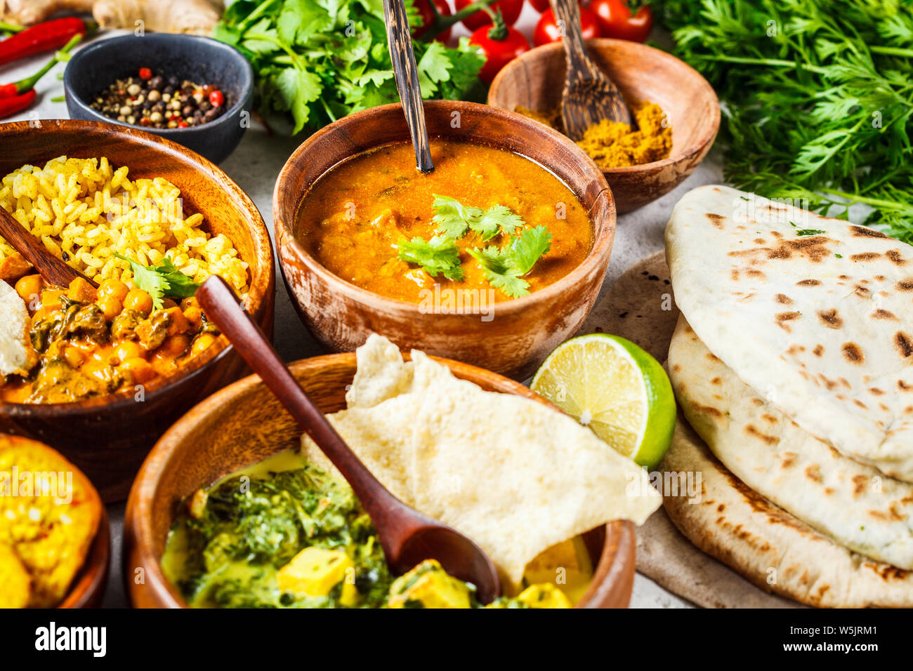 Essen traditionelle indische Küche. Dal, Palak Paneer, Käse Kugeln, Curry, Reis, Chapatis, Chutney in hölzernen Schüsseln auf weißem Hintergrund. Stockfoto