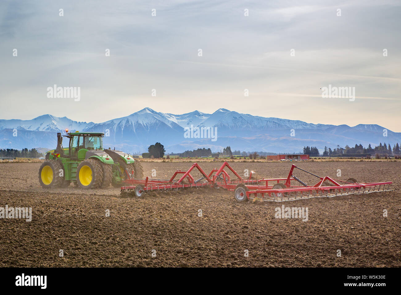 Sheffield, Canterbury, Neuseeland, 27. Juli 2019: Ein großes, modernes, John Deere Traktor schleppt eine Bodenfräse, in einem Feld im Winter Stockfoto