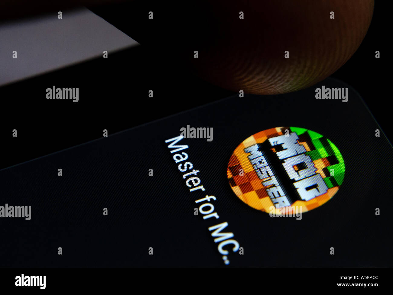 Minecraft Master MOD App auf dem Bildschirm des Smartphones mit sichtbaren Pixel und die Finger über Sie zu starten. Stockfoto