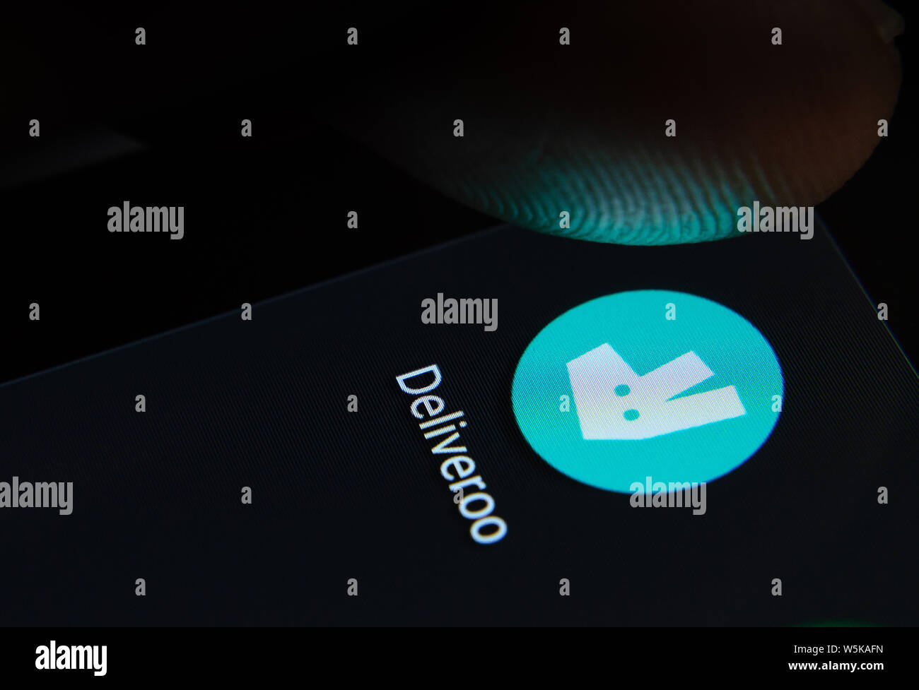 Deliveroo App auf dem Bildschirm des Smartphones mit sichtbaren Pixel und die Finger über Sie zu starten. Stockfoto