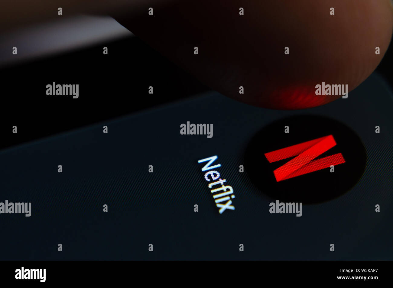 Netflix App auf dem Bildschirm des Smartphones mit sichtbaren Pixel und die Finger über Sie zu starten. Stockfoto