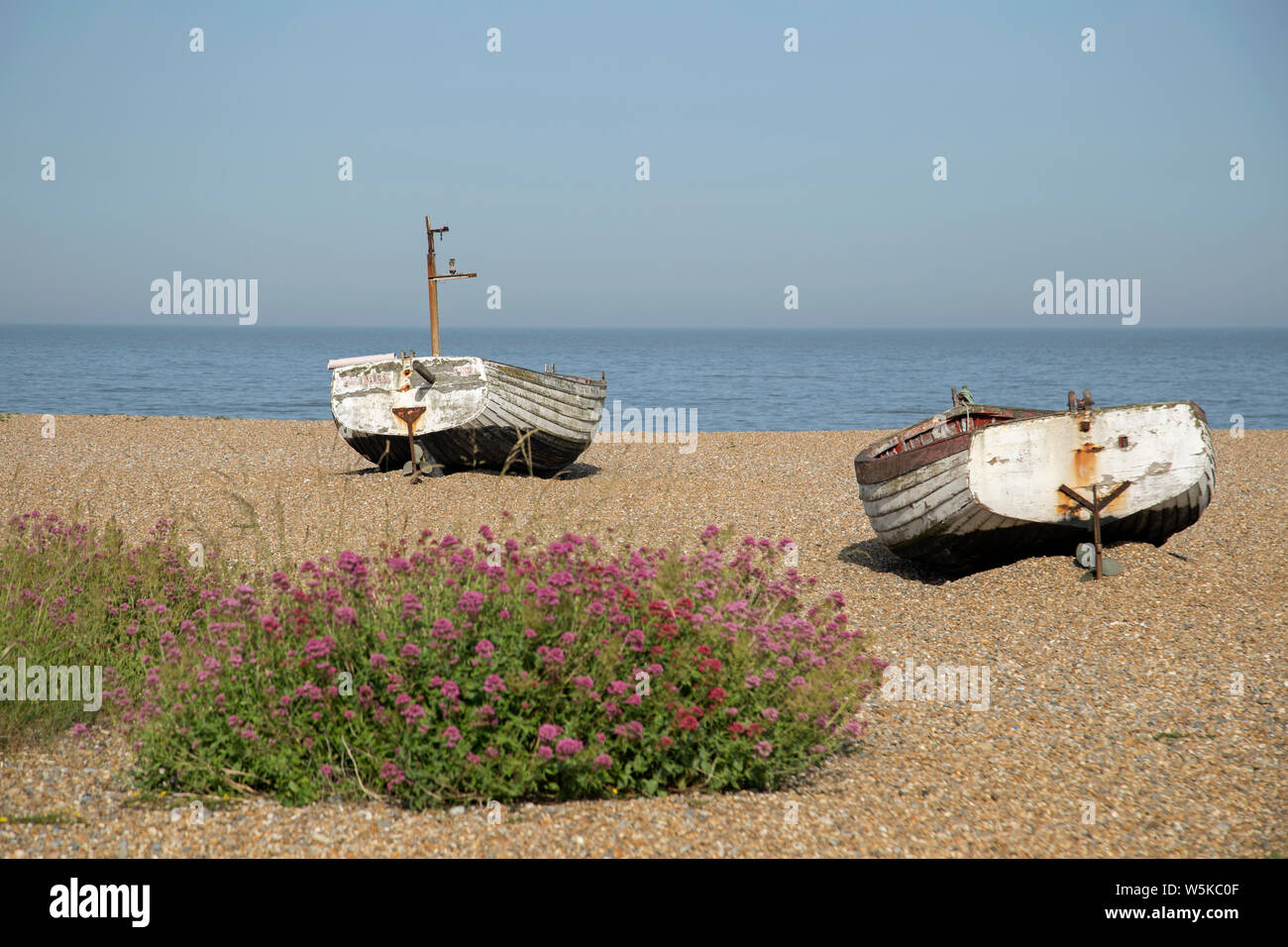 Zwei Ruderboote auf dem Kiesstrand an Alburgh, Suffolk, England gestrandet auf einem hellen, sonnigen Tag. Stockfoto