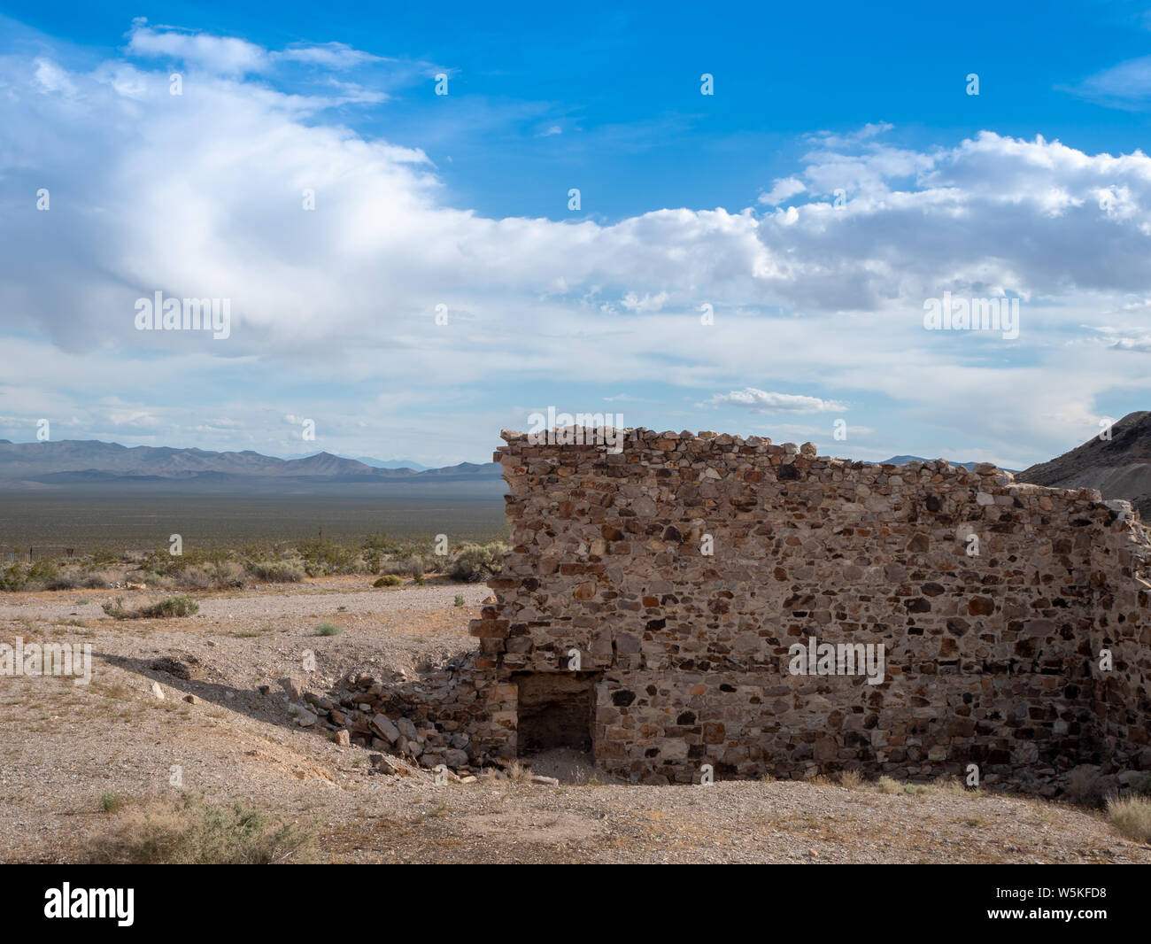 Reste einer Mauer aus Stein, die in den Ruinen eines Gebäudes in der Wüste Geisterstadt Rhyolith, Nevada Stockfoto