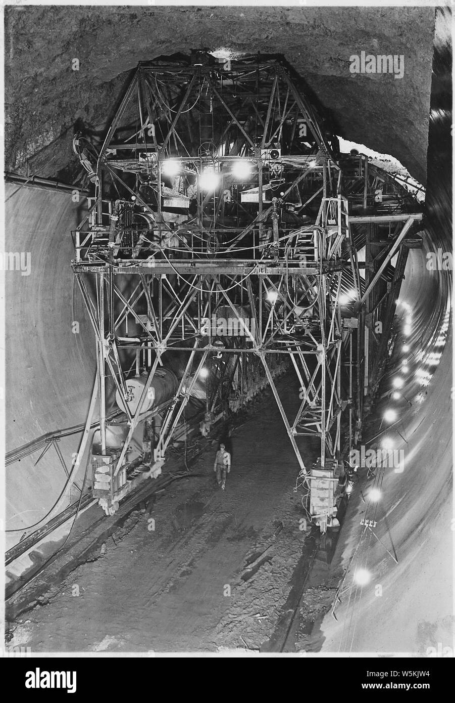 Konkrete Waffe Beförderung bei der Platzierung von 110 Grad top-arch Beton in der Abzweigung Tunnel verwendet; Umfang und Inhalt: Foto aus Band 2 einer Reihe von Fotoalben dokumentiert den Bau des Hoover Dam, Boulder City, Nevada. Vollständige Titelzeile des Foto liest: konkrete Waffe Beförderung bei der Platzierung von 110 Grad top-arch Beton in der Abzweigung Tunnels verwendet. Beton ist geschleppten Stapler im Dump-Eimer unter Beförderung zum oberen Deck von brückenkran Betrieb über den Kopf gehoben, in Trichter entleert und in Formen, die durch komprimierte Luft gezwungen durch zwei 8-Zoll Stahl und die Gummirohre. Zwei Gun Unit Stockfoto