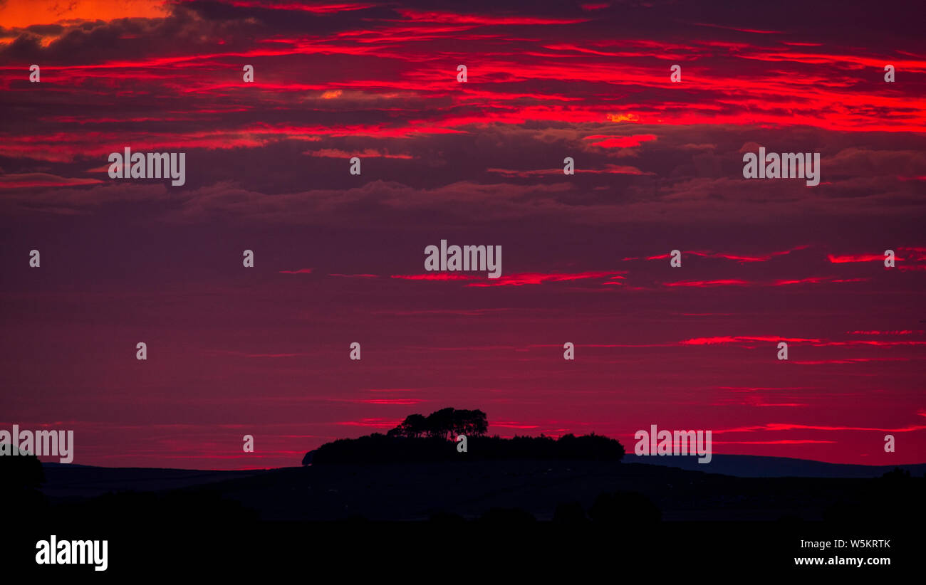 Wetter Großbritannien: spektakulären Sonnenuntergang über Minnning niedrigen Hügel historischen England Monument mit einem chambered Grab & zwei Schüssel Schubkarren, Peak District, Großbritannien Stockfoto